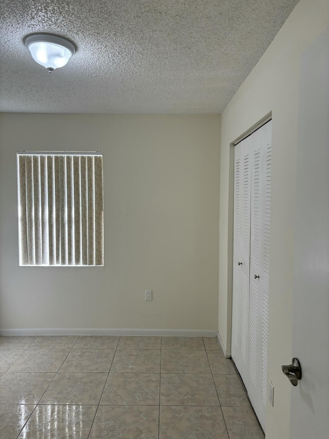 tiled empty room with a textured ceiling