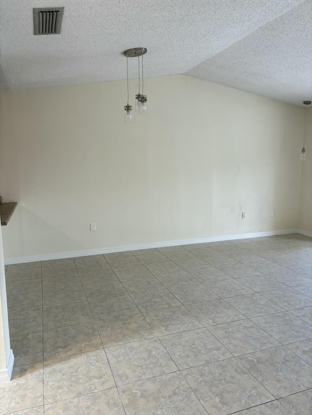 tiled empty room featuring vaulted ceiling and a textured ceiling