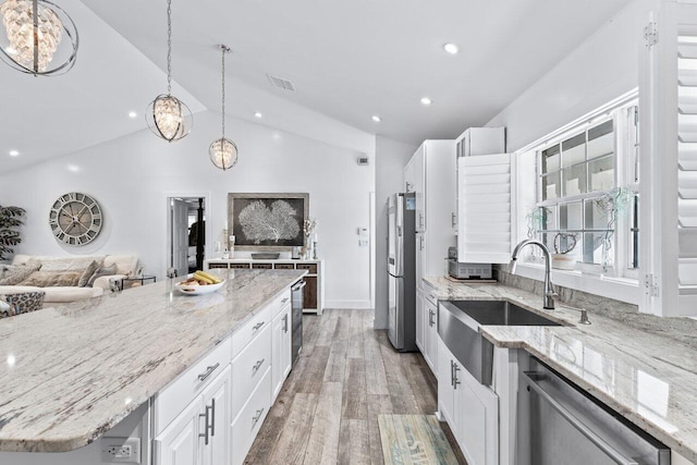 kitchen featuring stainless steel appliances, hardwood / wood-style floors, decorative light fixtures, lofted ceiling, and white cabinets