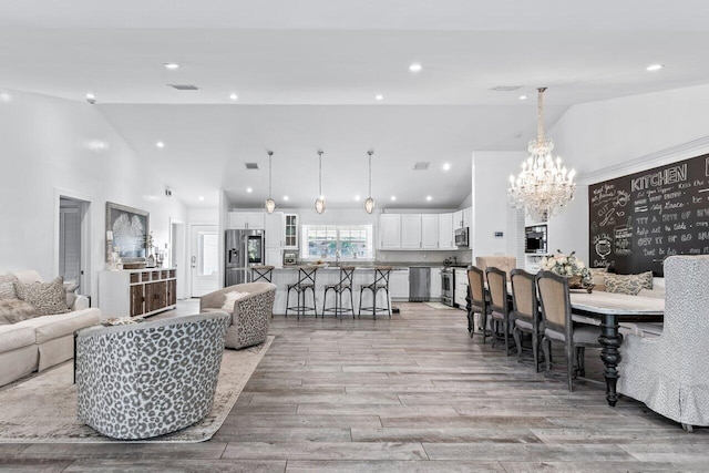 living room featuring a notable chandelier, light hardwood / wood-style floors, and high vaulted ceiling