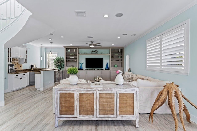 living room featuring light hardwood / wood-style floors, ceiling fan, crown molding, and sink