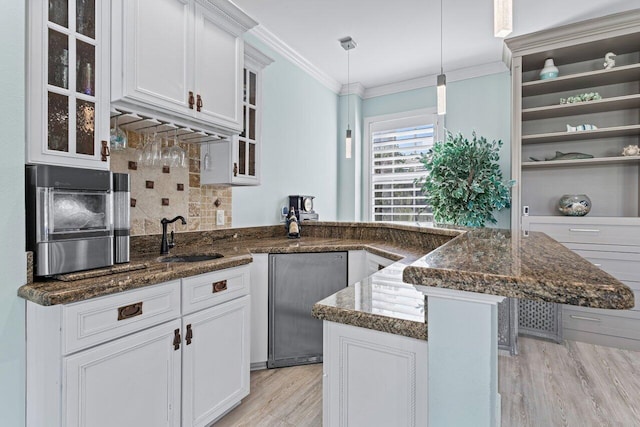 kitchen featuring decorative backsplash, light wood-type flooring, sink, pendant lighting, and white cabinetry