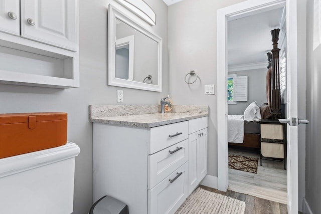 bathroom featuring hardwood / wood-style flooring, vanity, toilet, and crown molding