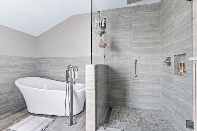 bathroom with hardwood / wood-style floors, vaulted ceiling, tile walls, and independent shower and bath