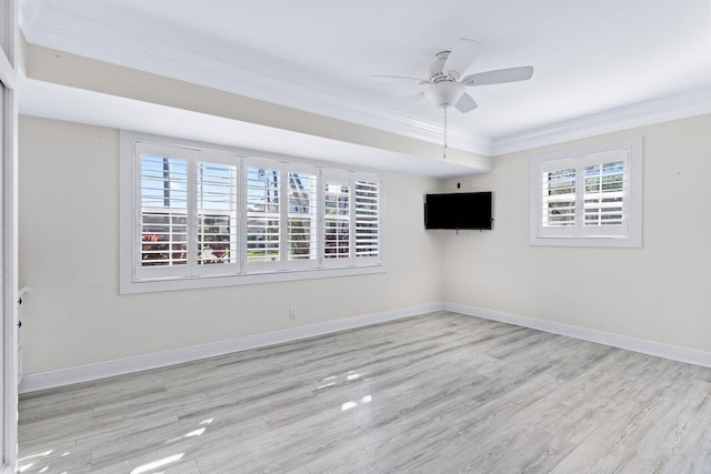 empty room with ceiling fan, ornamental molding, a healthy amount of sunlight, and light hardwood / wood-style floors