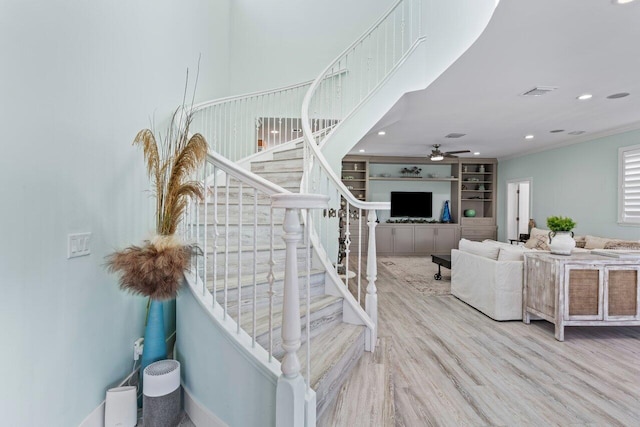 stairs with hardwood / wood-style flooring, ceiling fan, and built in features