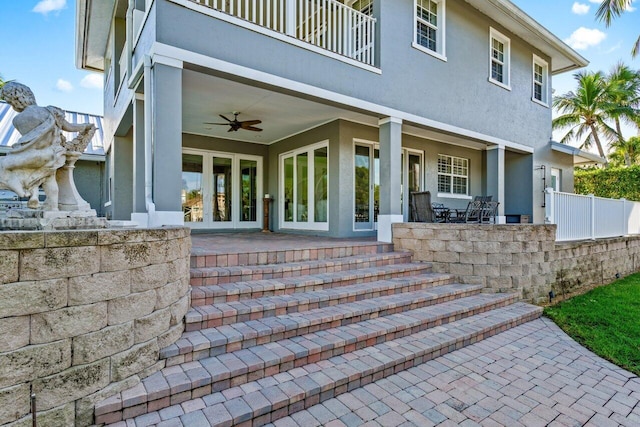 entrance to property with a patio area, ceiling fan, french doors, and a balcony