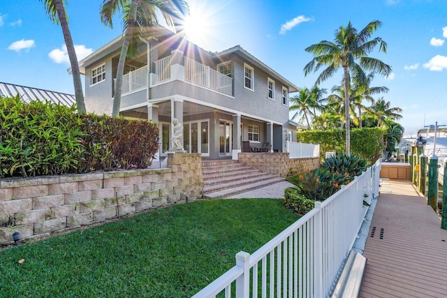 back of property with a yard and a balcony