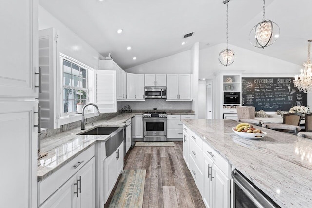 kitchen with stainless steel appliances, dark wood-type flooring, an inviting chandelier, white cabinets, and lofted ceiling