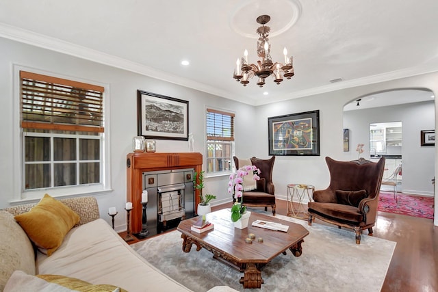 living area featuring baseboards, arched walkways, wood finished floors, and ornamental molding