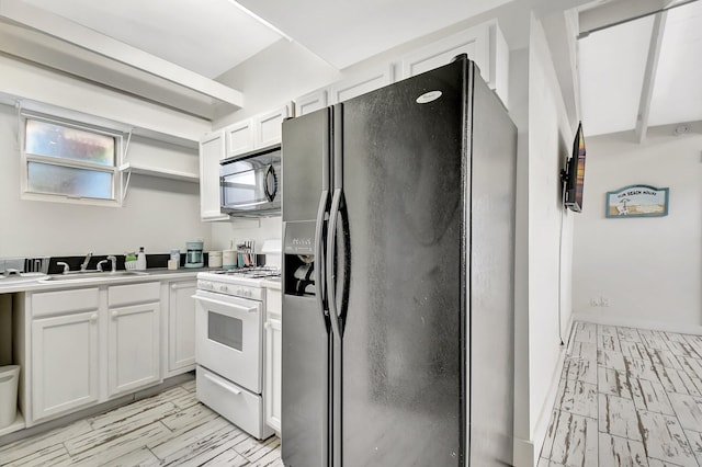 kitchen featuring white gas range, stainless steel microwave, black refrigerator with ice dispenser, white cabinets, and a sink