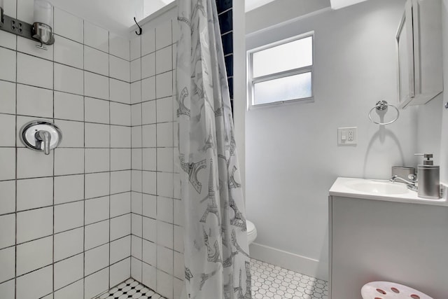 full bathroom with toilet, baseboards, a tile shower, and vanity