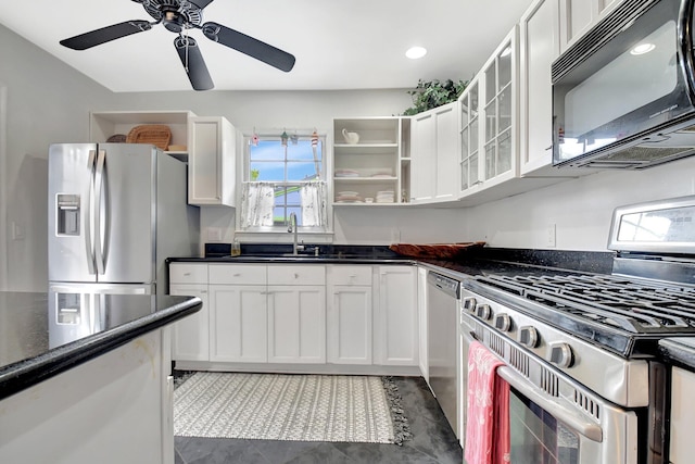 kitchen featuring dark countertops, appliances with stainless steel finishes, glass insert cabinets, white cabinetry, and a sink