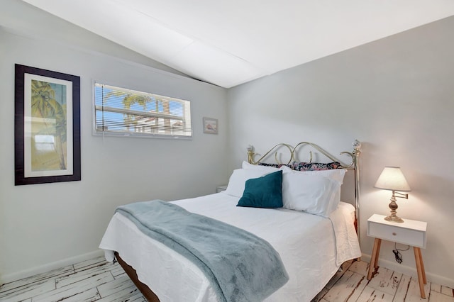 bedroom with vaulted ceiling, marble finish floor, and baseboards