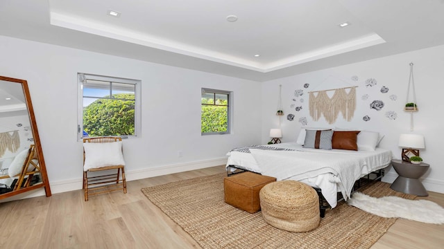 bedroom featuring light hardwood / wood-style floors and a raised ceiling