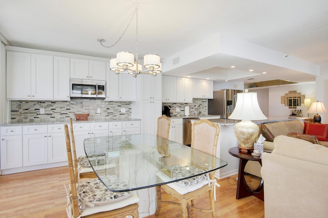 dining room with a tray ceiling, light hardwood / wood-style flooring, and a notable chandelier