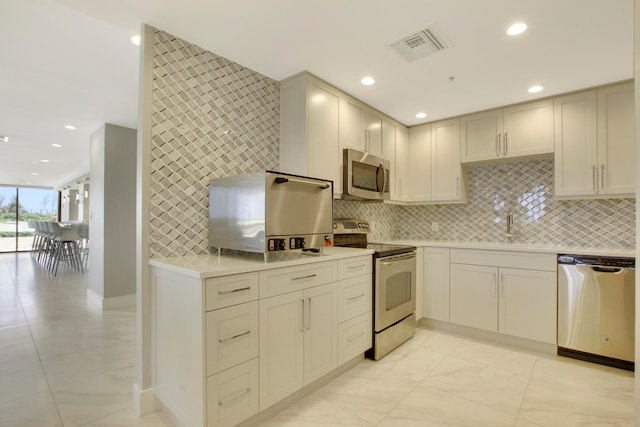 kitchen with backsplash, appliances with stainless steel finishes, and sink