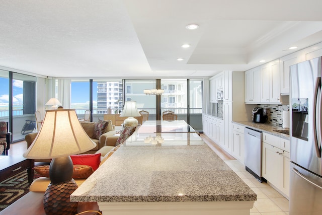 kitchen with stainless steel appliances, light stone countertops, and white cabinets