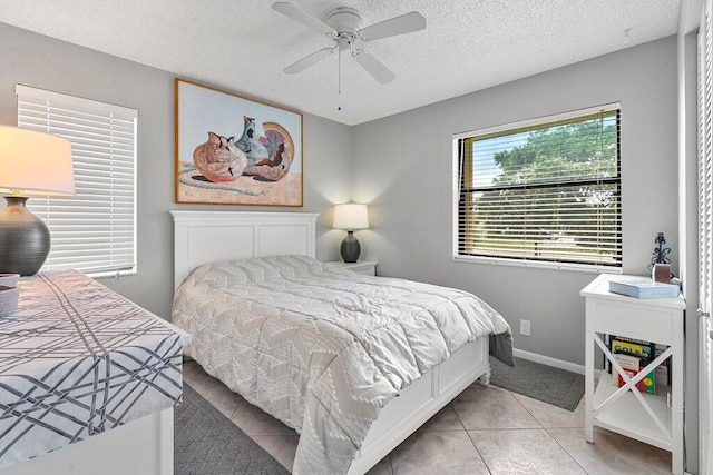 tiled bedroom with ceiling fan and a textured ceiling