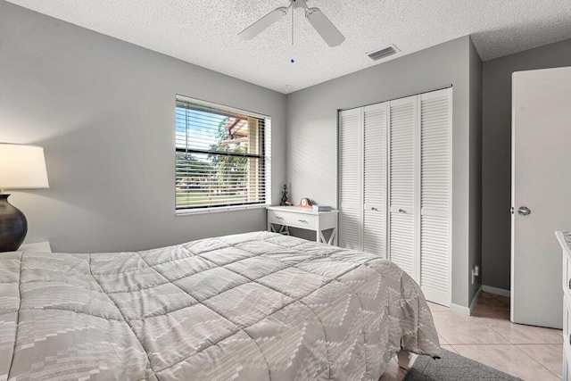 bedroom with light tile patterned floors, ceiling fan, a textured ceiling, and a closet