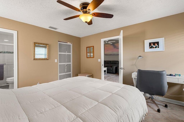bedroom with a textured ceiling, light tile patterned floors, ceiling fan, and ensuite bathroom