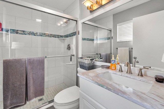 bathroom with toilet, vanity, and a shower with shower door