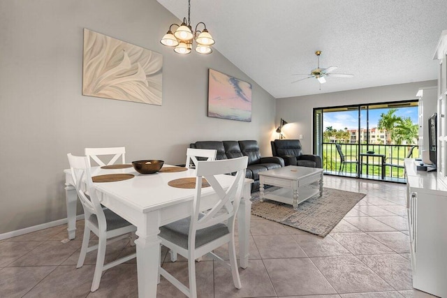 dining space with ceiling fan with notable chandelier, a textured ceiling, light tile patterned floors, and lofted ceiling