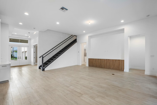 unfurnished living room with french doors and light hardwood / wood-style flooring