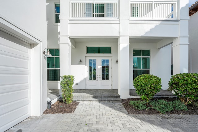 entrance to property featuring french doors, a balcony, and a garage