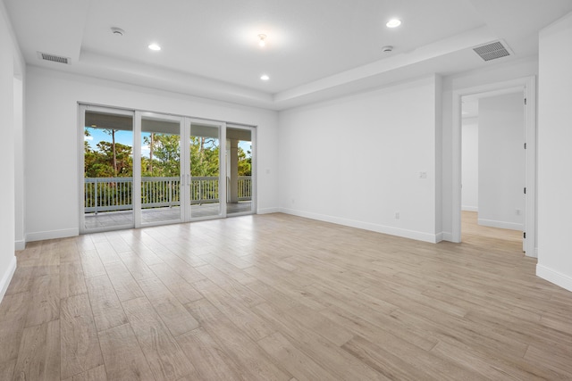 empty room with a raised ceiling and light wood-type flooring