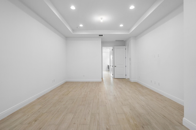 empty room featuring a raised ceiling and light hardwood / wood-style floors