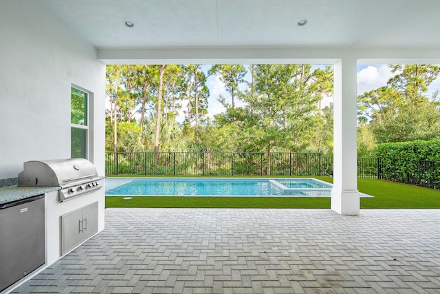 view of pool with a patio area, a lawn, exterior kitchen, and a grill