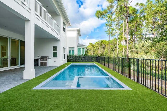 view of pool with a lawn, a patio area, and an outdoor kitchen