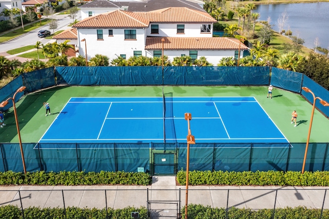 view of sport court with a water view and basketball hoop