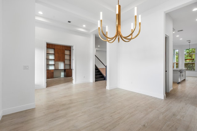 unfurnished dining area with an inviting chandelier and light wood-type flooring