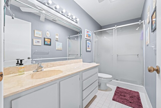 bathroom with toilet, vanity, tile patterned flooring, and a shower with door