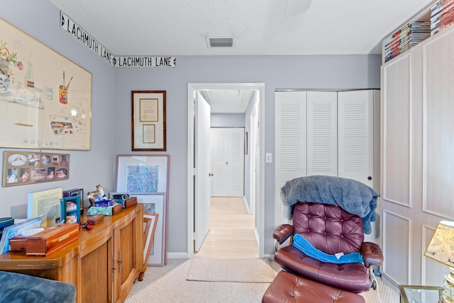 sitting room with light hardwood / wood-style floors and a textured ceiling