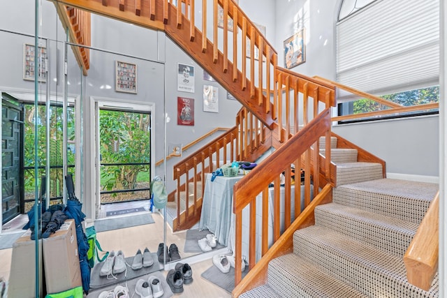 stairway with a high ceiling and wood-type flooring