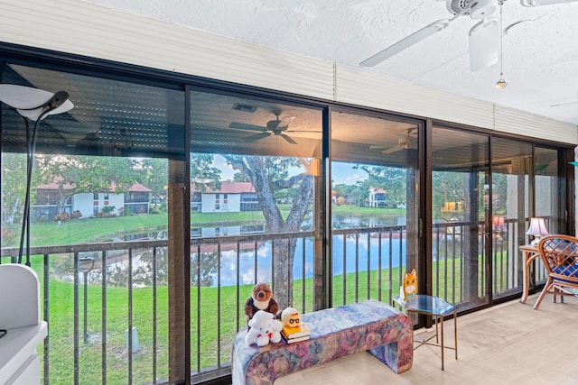 sunroom with a water view and ceiling fan