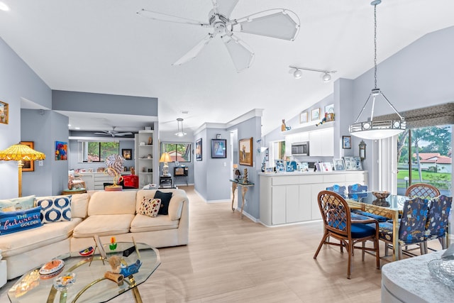 living room featuring ceiling fan, rail lighting, and lofted ceiling