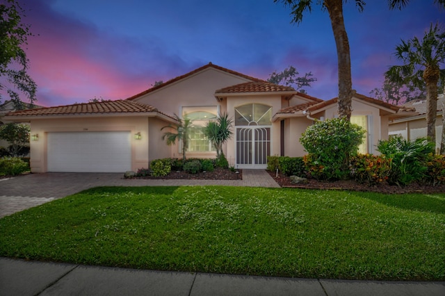 mediterranean / spanish-style home featuring a lawn and a garage