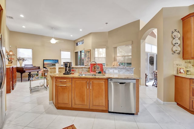 kitchen featuring sink, tasteful backsplash, light stone countertops, ceiling fan, and stainless steel dishwasher