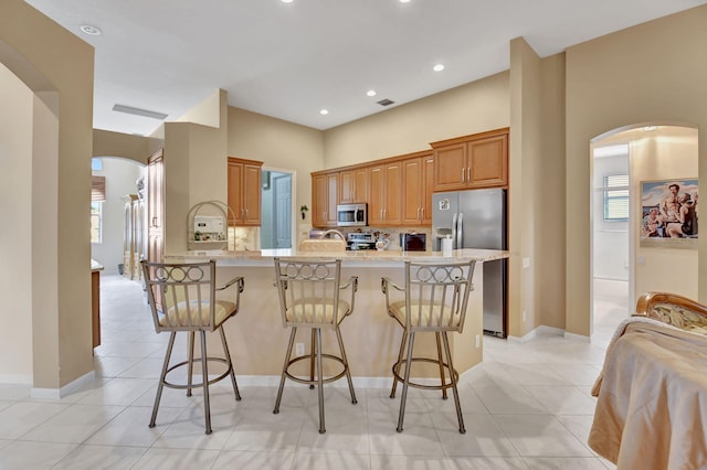 kitchen featuring light tile patterned flooring, appliances with stainless steel finishes, and a breakfast bar