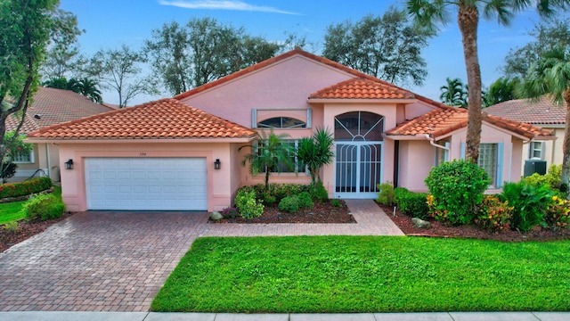 mediterranean / spanish-style house with a garage and a front lawn