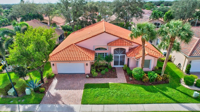 mediterranean / spanish house featuring a garage and a front yard