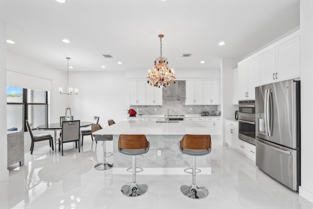 kitchen with extractor fan, light countertops, appliances with stainless steel finishes, a kitchen bar, and an inviting chandelier