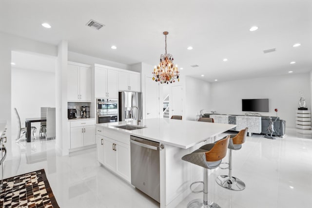 kitchen with a kitchen island with sink, a sink, visible vents, white cabinetry, and appliances with stainless steel finishes