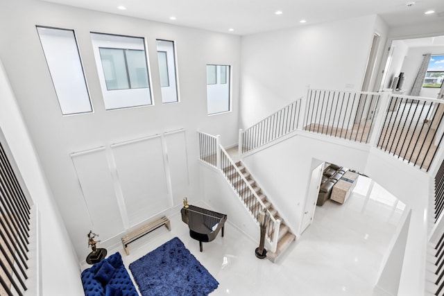 staircase with a towering ceiling and recessed lighting