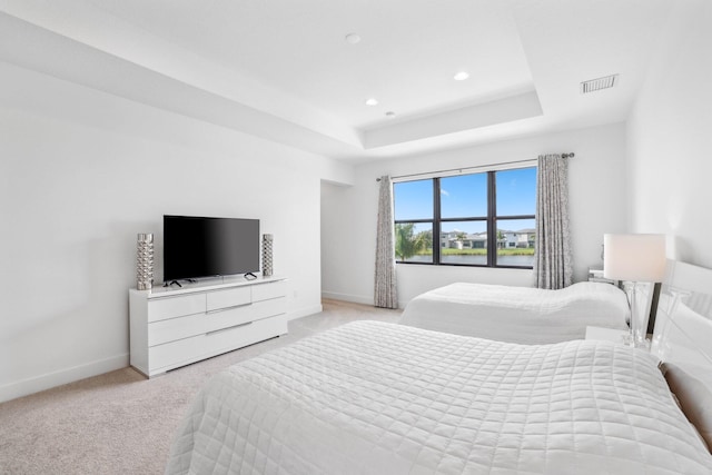 bedroom featuring light carpet, baseboards, visible vents, a tray ceiling, and recessed lighting