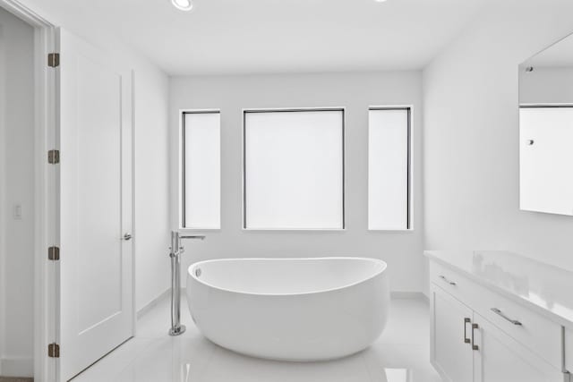 bathroom with recessed lighting, a soaking tub, vanity, and tile patterned floors